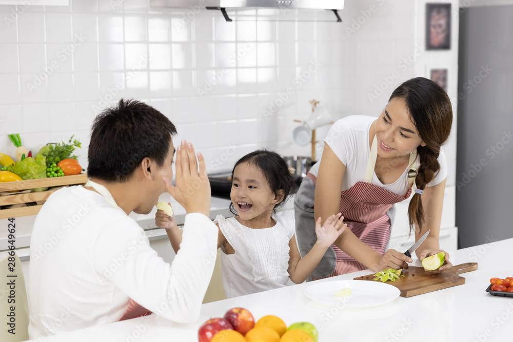Happy Asian family make a cooking. Father, Mother and Daughter are preparing fruit, green apple in the kitchen at home. Healthy food concept and happy holidays Happy Asian family make a cooking. Father, Mother and Daughter are preparing fruit, green apple in the kitchen at home. Healthy food concept and happy holidays