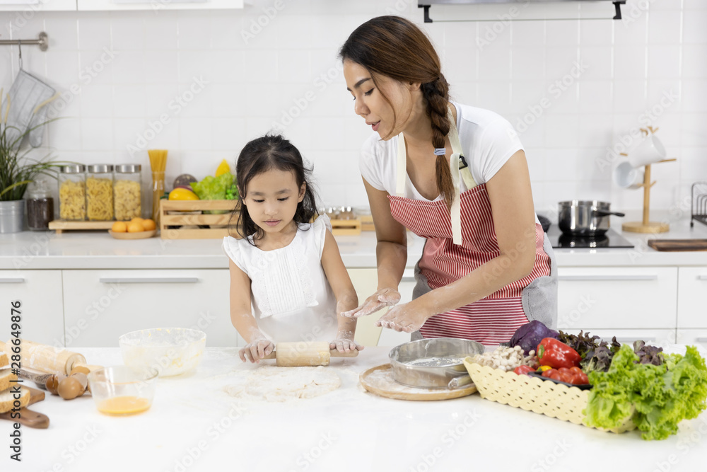 Happy Asian family Mother and Daughter are rolling pin thresh flour for making bakery in the kitchen in home. family cooking food Concept. Happy Asian family Mother and Daughter are rolling pin thresh flour for making bakery in the kitchen in home. family cooking food Concept.