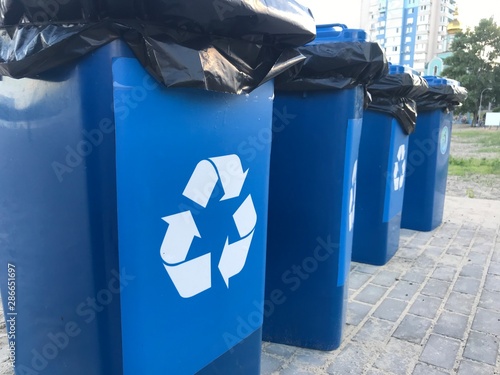 recycling bin with crumpled paper. blue trash cans on the beach in summer