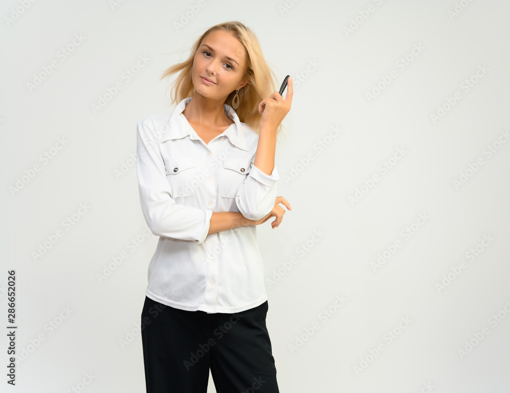 Studio portrait of a pretty blonde student girl, young woman in a white shirt on a white background. Talking, showing emotions. Studio portrait of a pretty blonde student girl, young woman in a white shirt on a white background. Talking, showing emotions.
