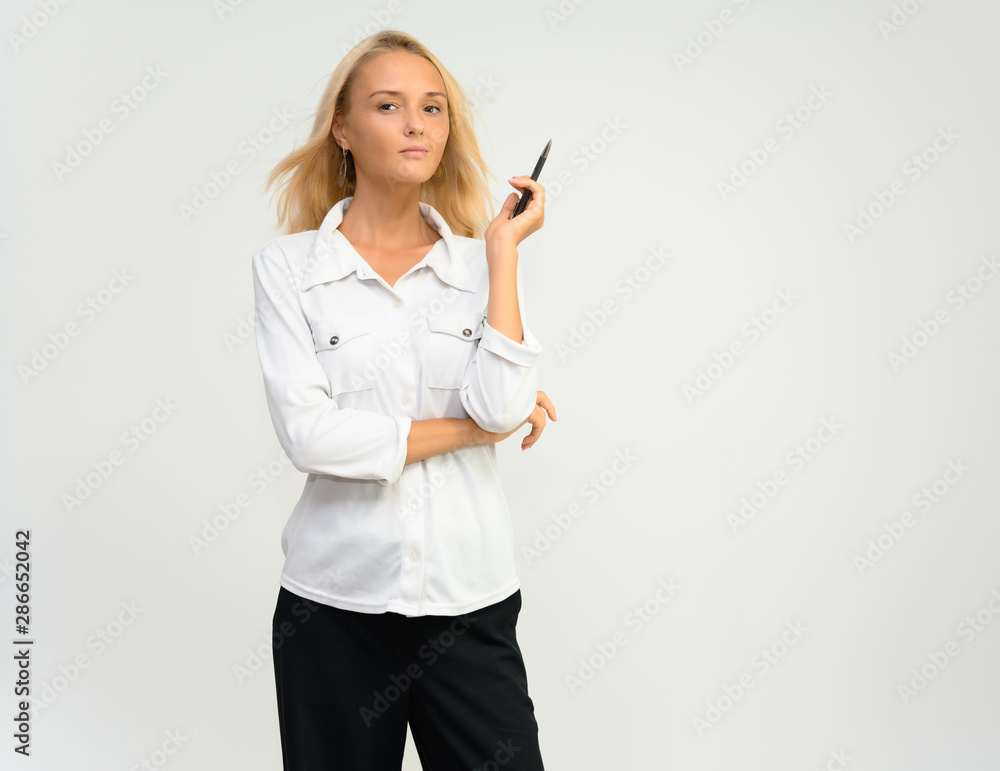 Studio portrait of a pretty blonde student girl, young woman in a white shirt on a white background. Talking, showing emotions.