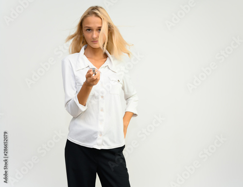 Studio portrait of a pretty blonde student girl, young woman in a white shirt on a white background. Talking, showing emotions.