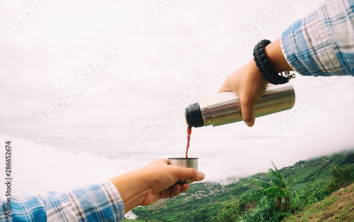 Pouring coffee from the thermos outdoors.