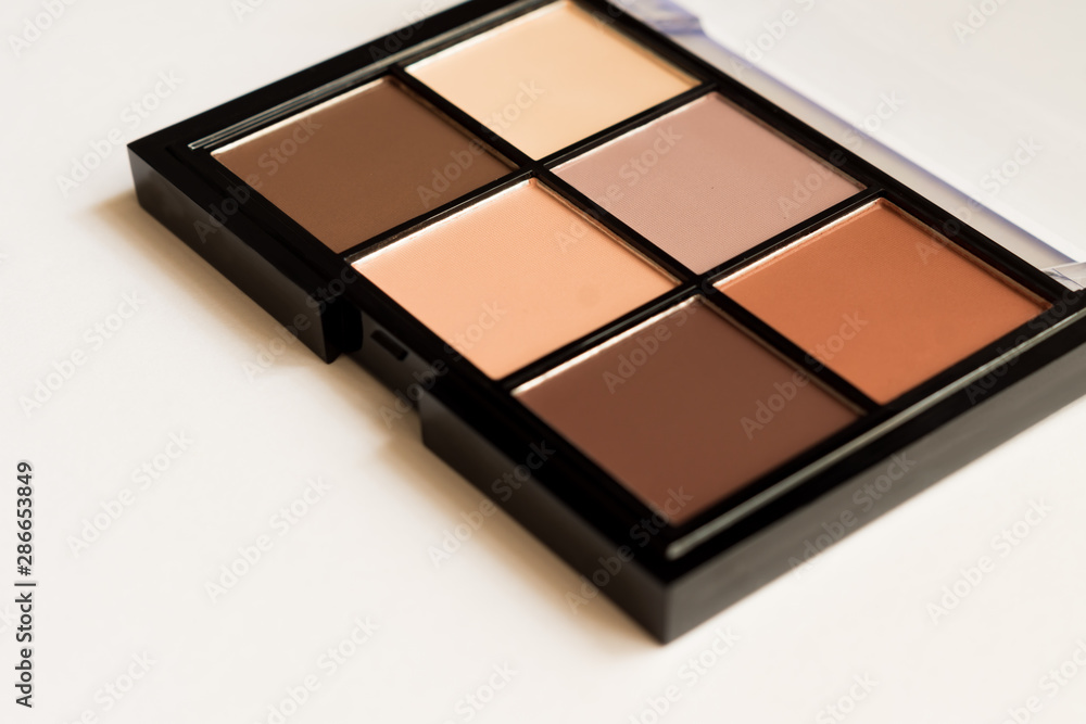 Natural look, Brown tone eye shadows make up palette in black case on white background. Selective focus Natural look, Brown tone eye shadows make up palette in black case on white background. Selective focus