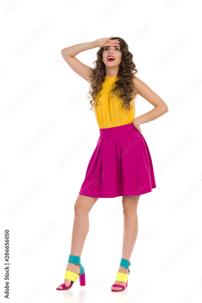 Surprised Young Woman In Colorful High Heels And Pink Mini Skirt Is Looking Up Surprised Young Woman In Colorful High Heels And Pink Mini Skirt Is Looking Up