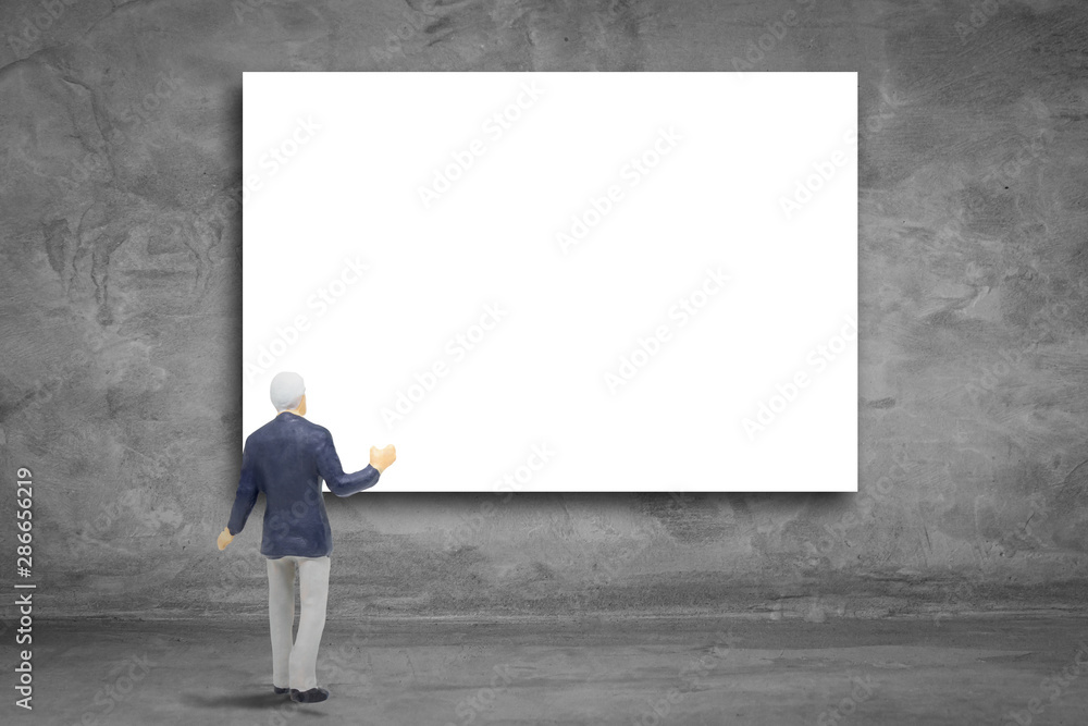 Business Idea Concept : Miniature figurine character as businessman standing and looking blank billboard hanging on concrete wall. Business Idea Concept : Miniature figurine character as businessman standing and looking blank billboard hanging on concrete wall.
