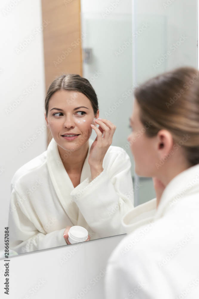 Woman holding cream in hands, standing at bathroom Woman holding cream in hands, standing at bathroom