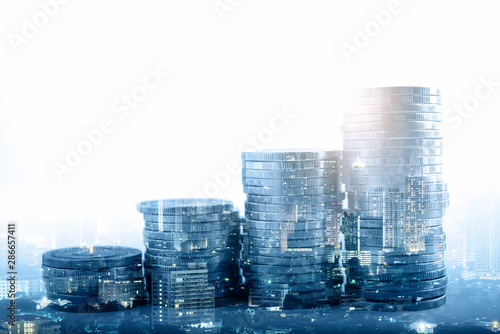 Double exposure of city night and stack of coins for finance investor, investment and banking concept