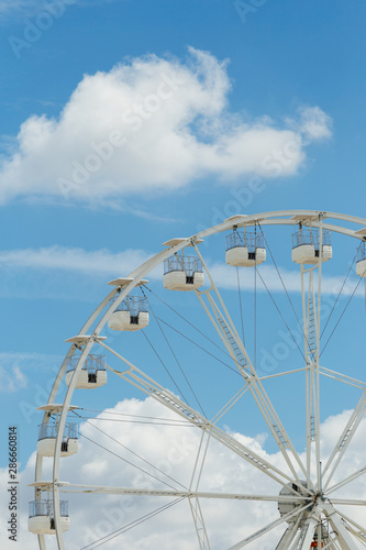 Ferris wheel on the blue cloudy sky. Background concept of happy holidays time. © sergiymolchenko