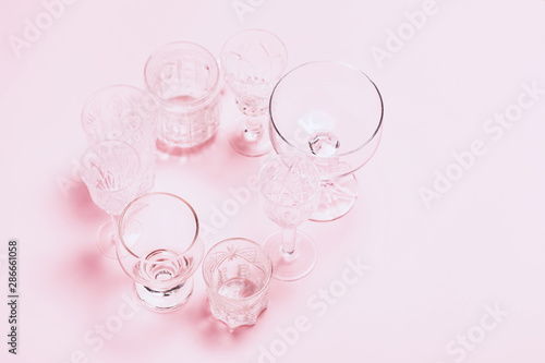 Many empty glasses on pink background. Top view  flat lay.