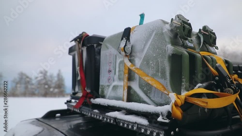Fuel can and equipment strapped on roof rack of car in winter.