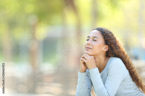 Slika na platnu Mixed-race woman relaxing meditating in a park