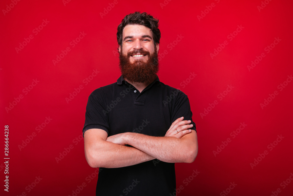 Handsome bearded man is smiling at the camera with arms crossed. Handsome bearded man is smiling at the camera with arms crossed.
