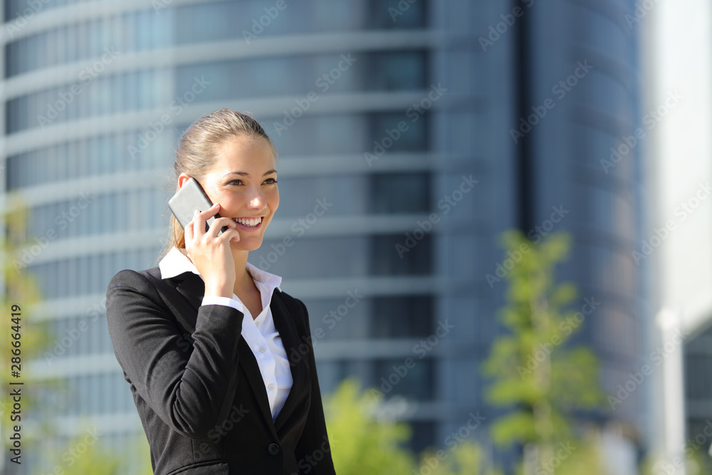 Happy businesswoman talking on phone walking