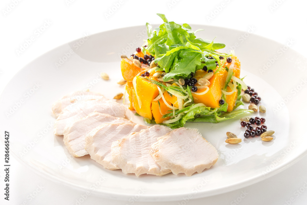 Roasted turkey fillet slices with pumpkin and greens on white plate isolated on white background Roasted turkey fillet slices with pumpkin and greens on white plate isolated on white background