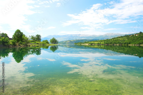Lake Peruca and mountain Svilaja in background. Clouds and trees reflection in Water. Croatia.