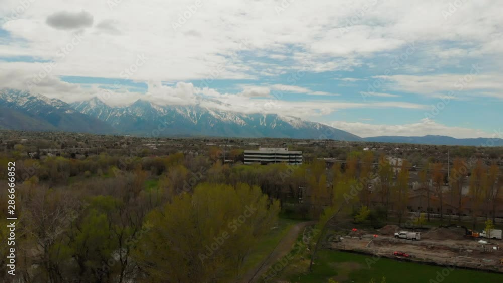 Salt Lake City Wasatch Mountains boom rising view reveal shot of buildings & freeways. Aerial drone footage. Overcast autumn day, snow in mountains. Salt Lake City Wasatch Mountains boom rising view reveal shot of buildings & freeways. Aerial drone footage. Overcast autumn day, snow in mountains.