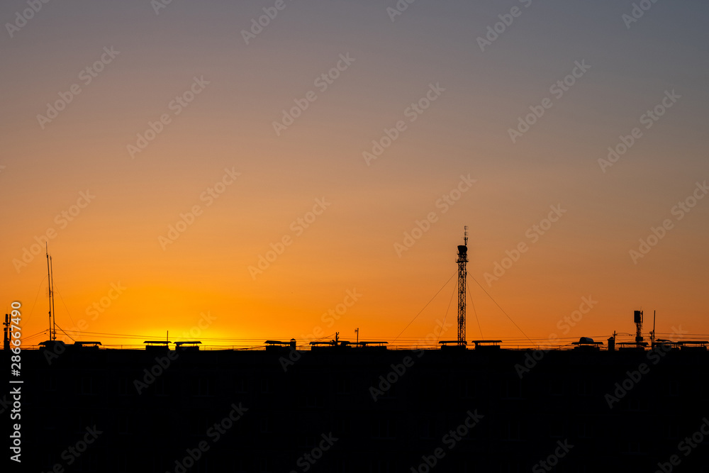 sunset city rooftops with antenna and lots of cables