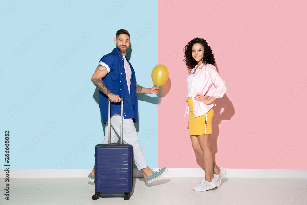 Young emotional caucasian couple in bright casual clothes posing on pink and blue background. Concept of human emotions, facial expession, relations, ad. Man and woman going to trip together. Young emotional caucasian couple in bright casual clothes posing on pink and blue background. Concept of human emotions, facial expession, relations, ad. Man and woman going to trip together.