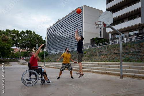 three boys, one of them in a wheelchair playing basketball