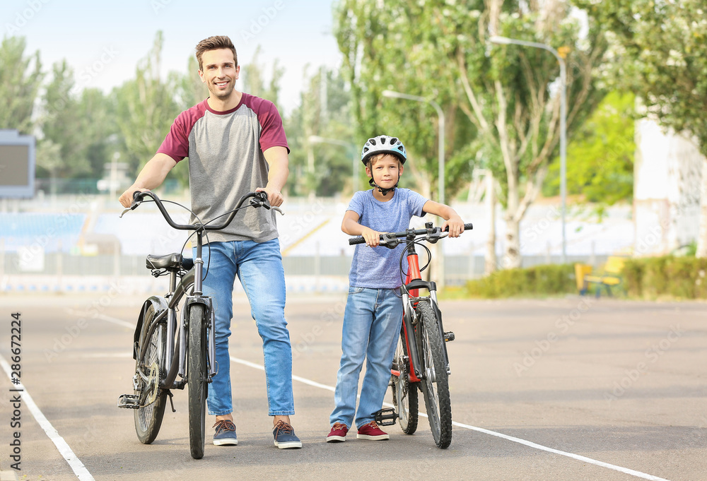 Obraz premium Happy father and son riding bicycles outdoors