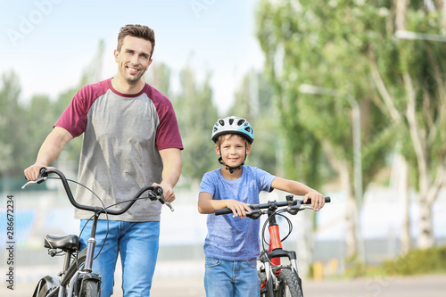 Happy father and son riding bicycles outdoors