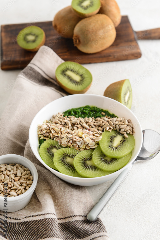 Bowl with tasty oat flakes and kiwi on white table Bowl with tasty oat flakes and kiwi on white table