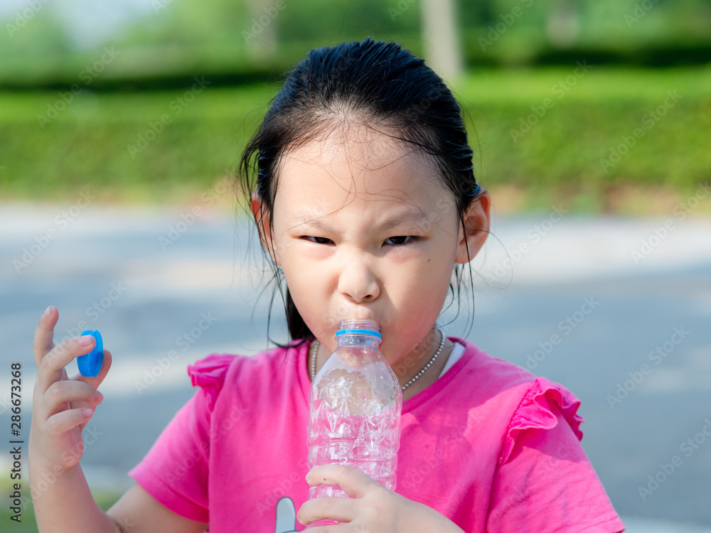 Happy Asian girl drinking a bottle of water outdoor. Happy Asian girl drinking a bottle of water outdoor.