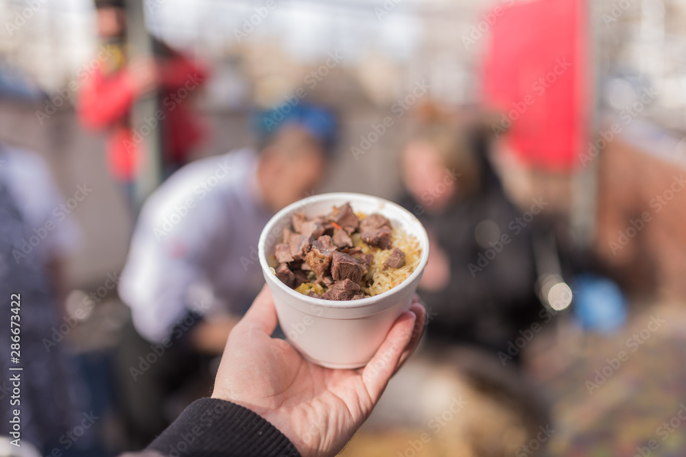 Hand holds bowl with meat and rice. Hand holds bowl with meat and rice.
