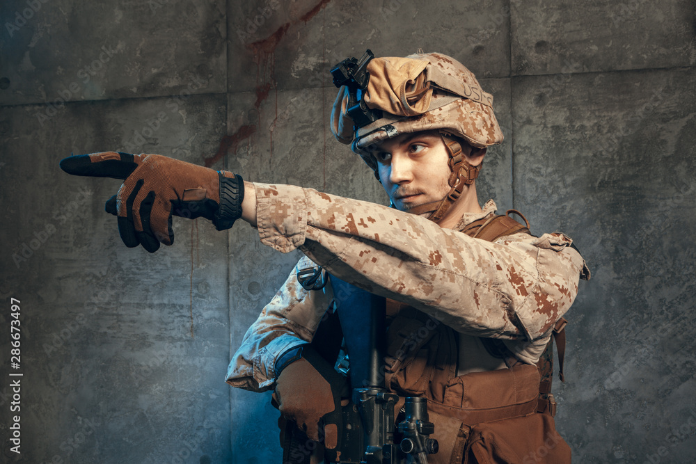 Fototapeta premium fully equipped army soldier in camo uniform and helmet, armed with pistol and assault service rifle