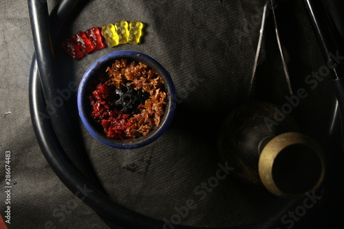 bowl with tobacco for hookah. berries on a black background 