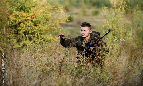 Bearded serious hunter spend leisure hunting. Man wear camouflage clothes nature background. Hunting permit. Hunter hold rifle. Hunting is brutal masculine hobby. Hunting and trapping seasons