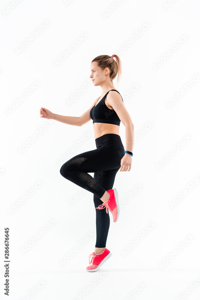Young sporty blond woman in a black sportswear jumping isolated over white background. Sport activity Young sporty blond woman in a black sportswear jumping isolated over white background. Sport activity