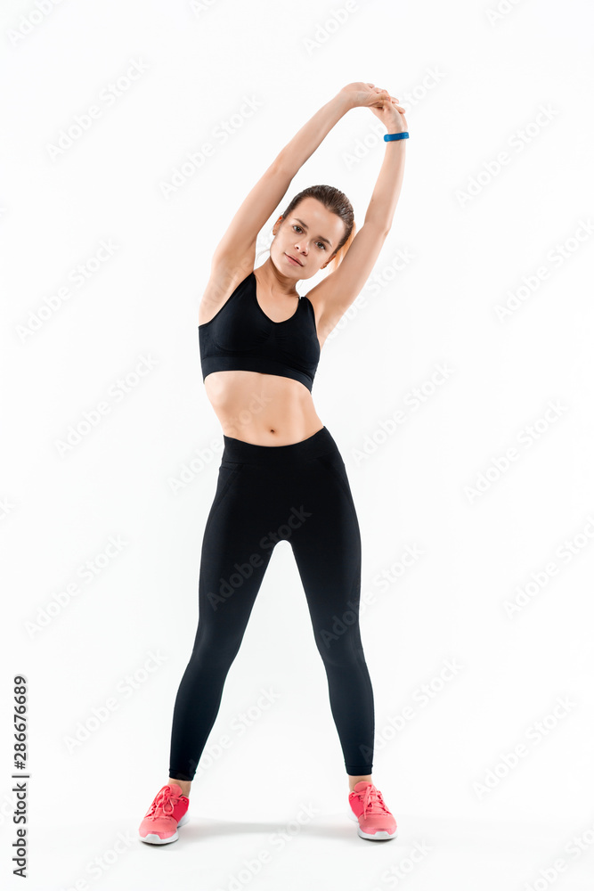 Young sporty blond woman in a black sportswear stretching after exercising isolated over white background.