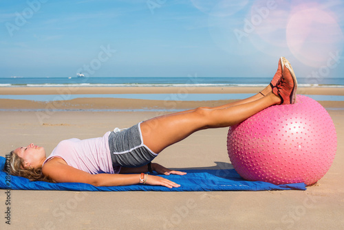 beautiful woman doing pilate ball on the sunny beach photo