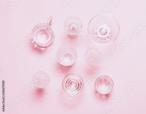 Many empty glasses on pink background. Top view, flat lay.