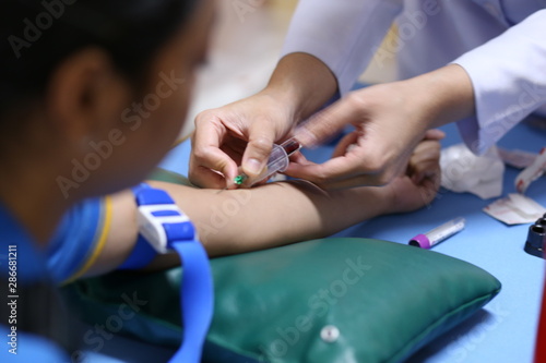 Thailand, Bangkok 2019/08/28. A health worker taking a blood sample from the vein by piercing the veinpunture and collecting blood into a test tube under negative pressure.