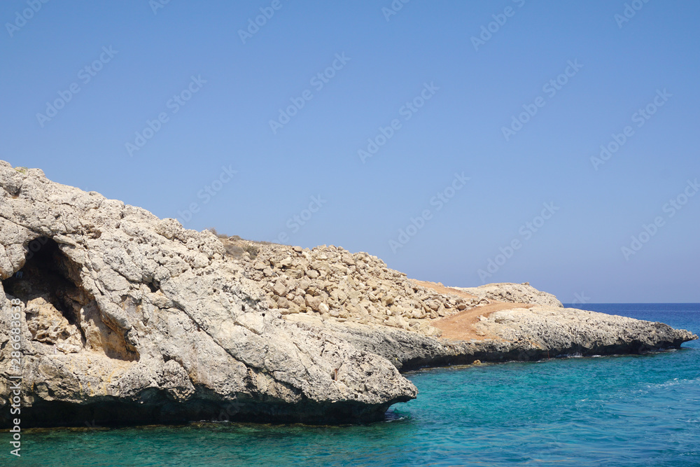 Fototapeta premium view of a small rock protruding into the sea on a Sunny day. Rest at sea, tourism, holidays. Beautiful view of the coast