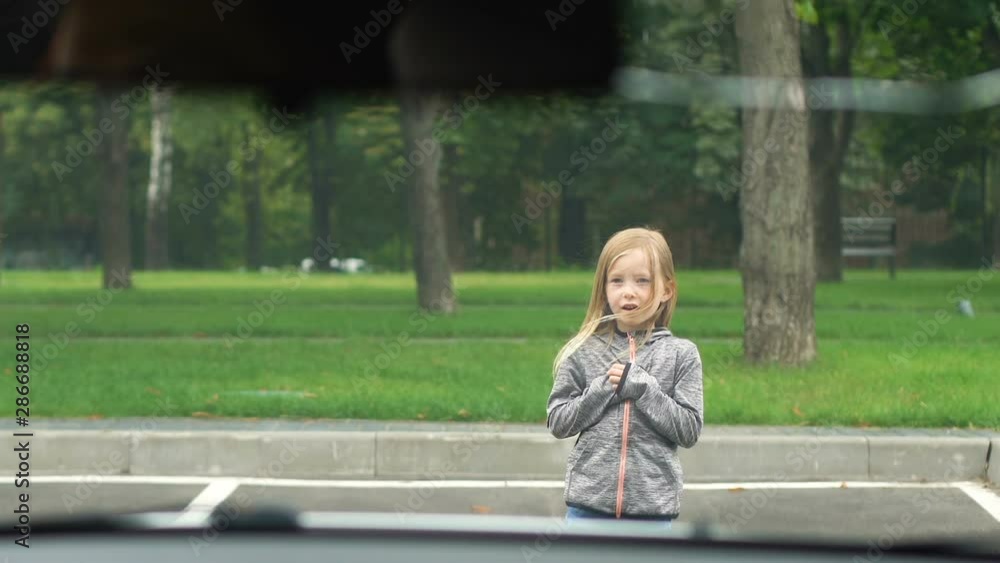 Carefree small girl running on parking front of driving car, traffic regulations Carefree small girl running on parking front of driving car, traffic regulations