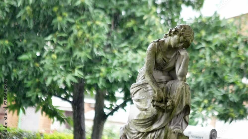 Female statue headstone in rainy cemetery. Angelic decorative carving guardian. Female statue headstone in rainy cemetery. Angelic decorative carving guardian.