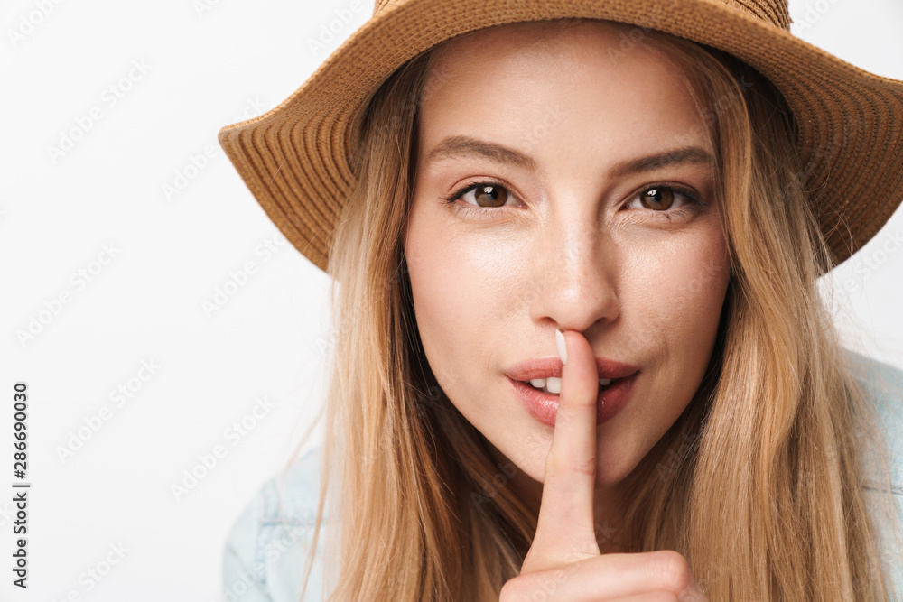 Young pretty woman wearing hat posing isolated over white wall background showing silence gesture. Young pretty woman wearing hat posing isolated over white wall background showing silence gesture.