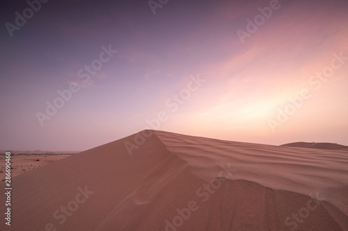 Sun set in dessert outside of Abu Dhabi with pink and red sky UAE 