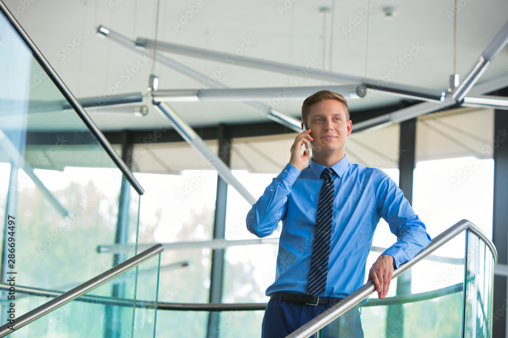 Smiling businessman using smartphone while standing at office
