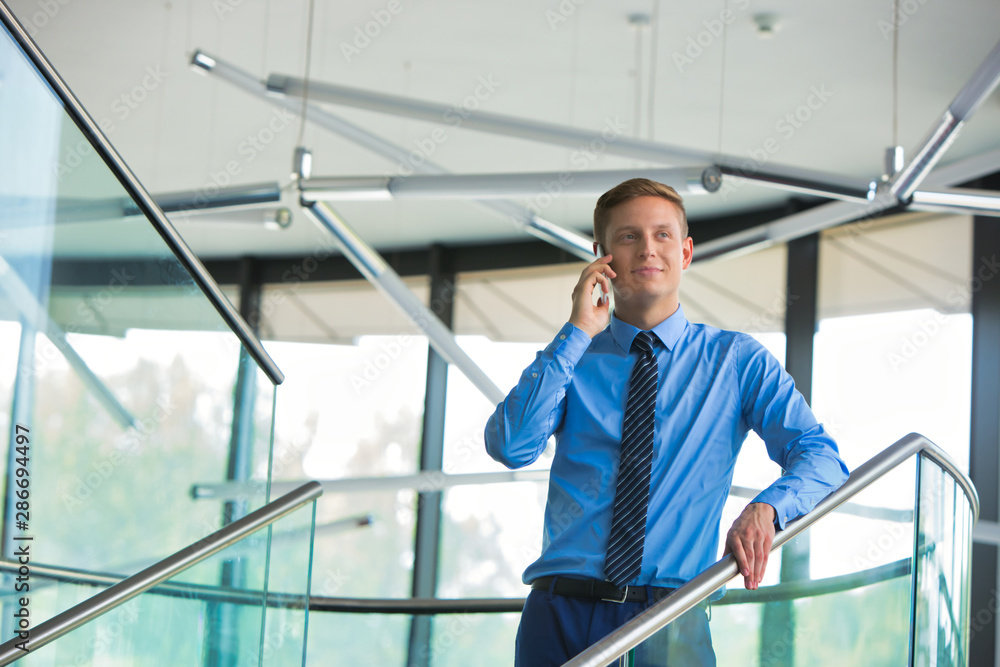 Smiling businessman using smartphone while standing at office Smiling businessman using smartphone while standing at office