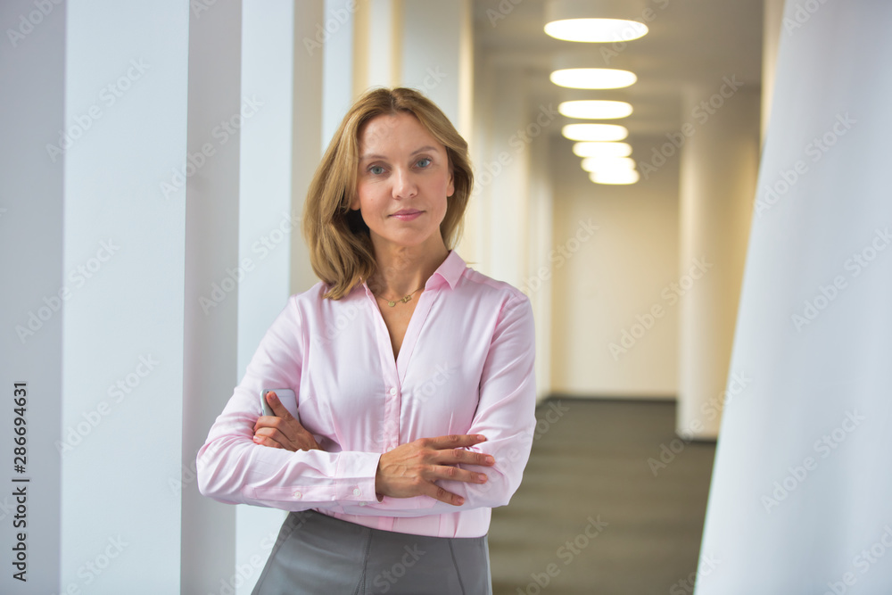 Portrait of confident businesswoman standing with arms crossed in corridor at office Portrait of confident businesswoman standing with arms crossed in corridor at office