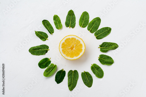 Composition of mint leaves, lemon and pieces of cane sugar on a white old concrete background.
