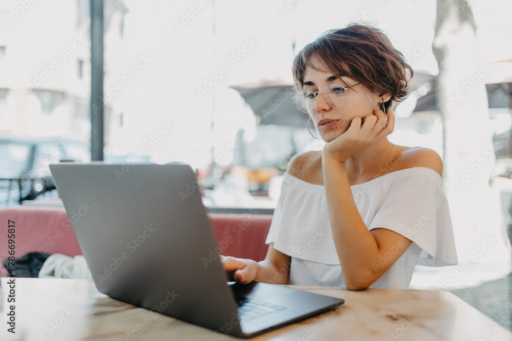 Beautiful woman using laptop in cafe outdoors Beautiful woman using laptop in cafe outdoors