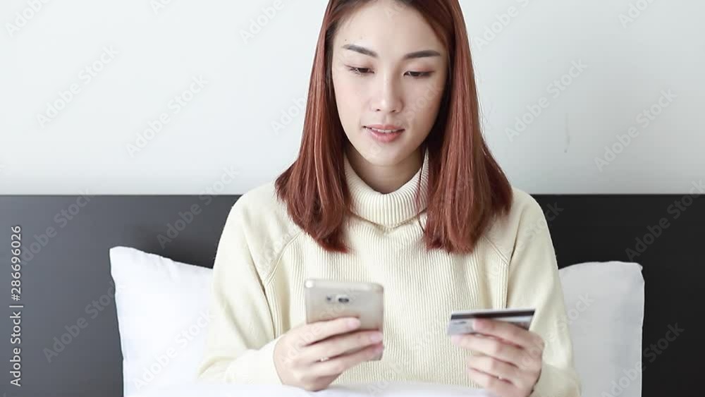 Beautiful Asian Women wearing yellow long-sleeved shirts, use credit cards and phone for online shopping. Beautiful Asian Women wearing yellow long-sleeved shirts, use credit cards and phone for online shopping.