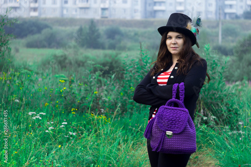 A woman in a tall hat with a purple backpack in the Park.