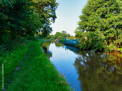 Barges nestled in to the banks of the Shropshire Union Canal near Whitchurch on a cloudless summer evening.